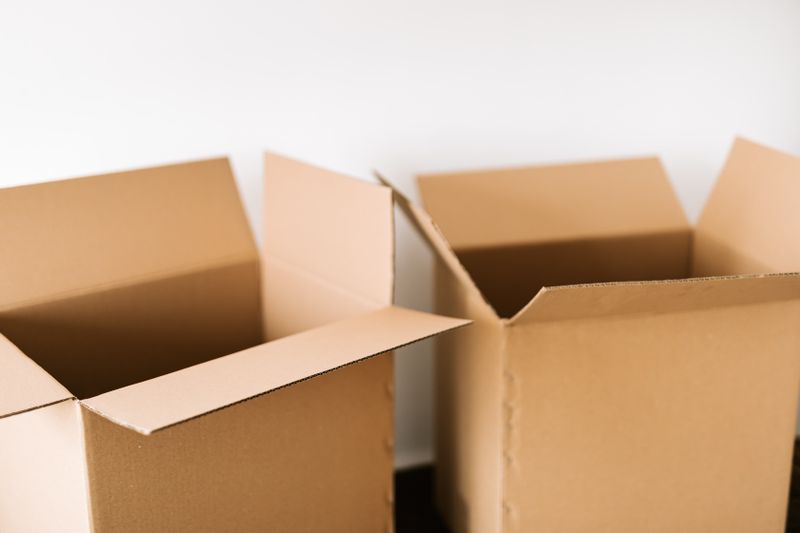 Two open cardboard boxes against a white wall