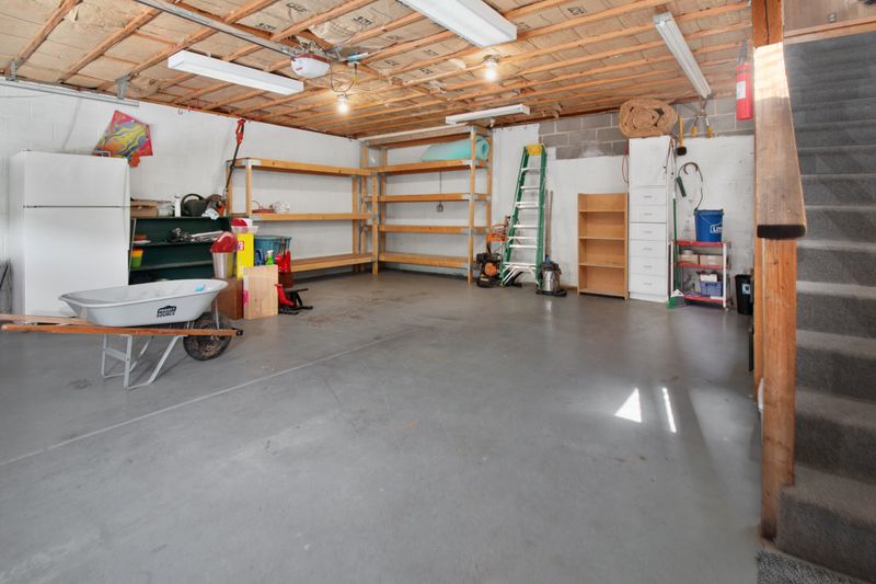A clean, spacious home garage with wooden storage shelves and a wheelbarrow