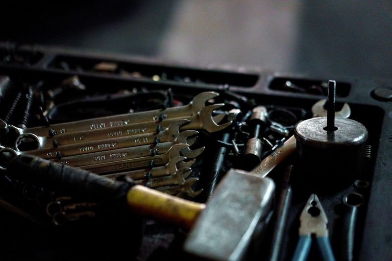A close-up of wrenches, a hammer, and pliers resting in a toolbox